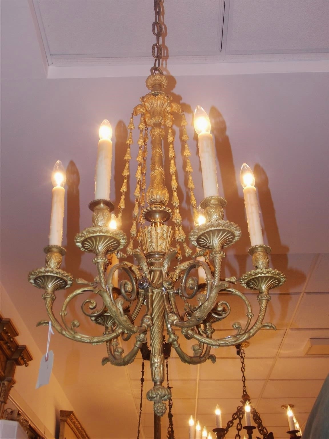 French gilt bronze six-light chandelier with decorative floral canopy, cascading bellflowers, scrolled acanthus floral arms, and centered column with an arrow and sheath motif. Early 19th century. Originally candle powered and has been electrified.