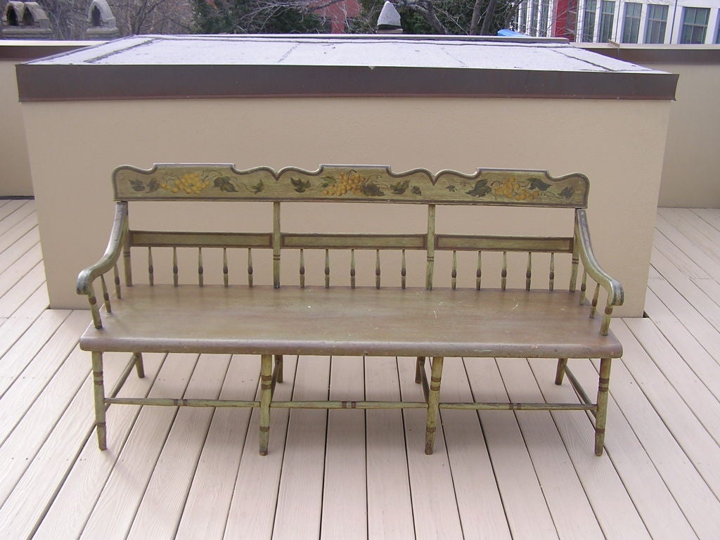 American carved wood and painted bench with grape vine motif, one board seat, scrolled arms, spindle carvings, and ending on turned painted legs. Fancy Furniture, Baltimore.  Early 19th Century.