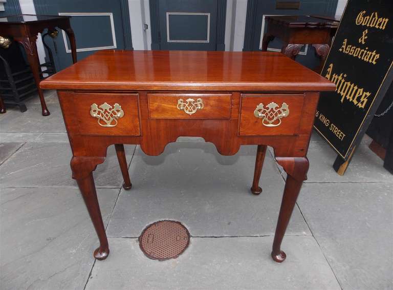 English Queen Anne mahogany three drawer  low boy with one board top, carved skirt and knee, original brasses and terminating on pad feet.  Late 18th Century