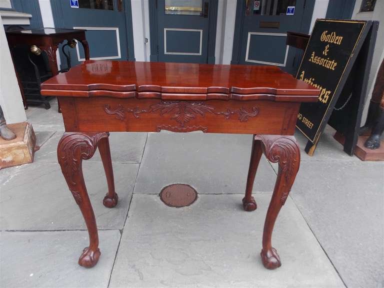 English Chippendale mahogany one board flip top game table with carved floral skirt, Acanthus carved knee, and terminating on ball and claw feet.  Late 18th Century