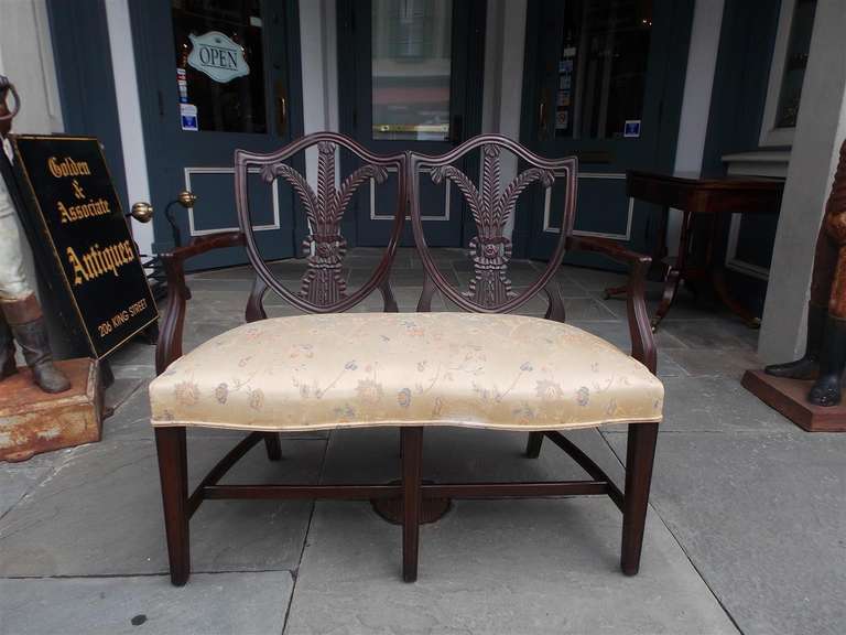 Divano inglese Chippendale in mogano con schienale a scudo e intagliato  Piume di Wales, motivi floreali a nastro e a campana, bracci a serpentina con nervature e terminali su gambe affusolate con barelle di collegamento. Fine del XVIII secolo