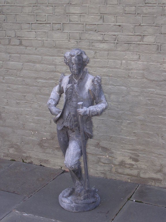 English Lead Statue of gentleman standing with garden tool in hand relaxing on circular plinth. Early 20th Century. 