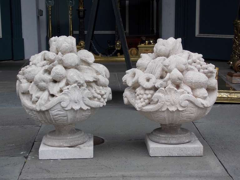 Pair of Italian hand carved sandstone fruit baskets resting on circular squared plinths. Early 19th Century