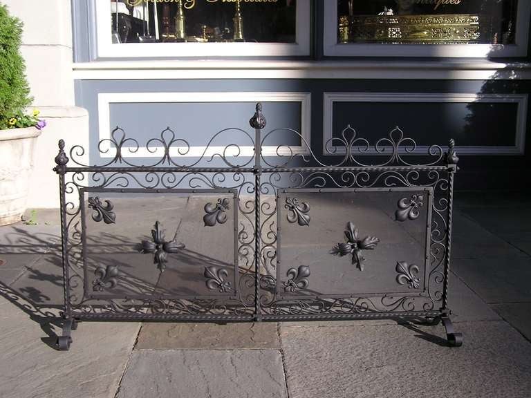 French wrought iron free standing two panel fire screen with scrolled decorative iron motif, Flur-de-le motif, and ending on standing scrolled feet. Dealers please call for trade price.