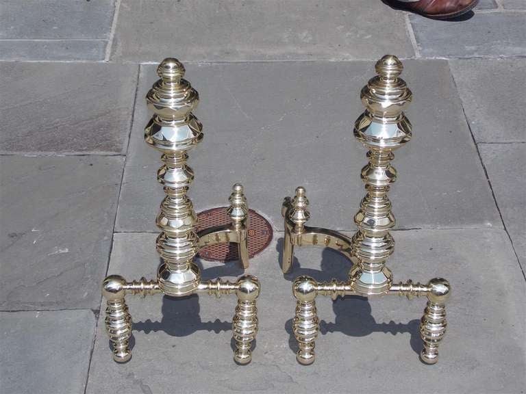 Pair of American  brass andirons with faceted finial tops, resting on turned bulbous legs, with matching faceted finial log stops. Signed  E. Smylie  NY.  Dealers please call for trade price.