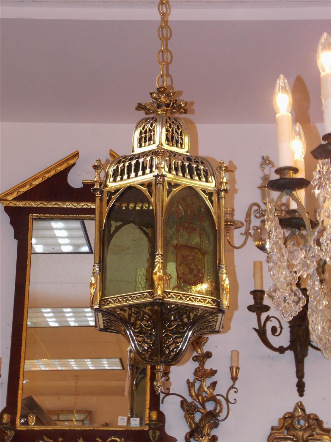 English brass royalty hexagon shaped hanging hall lantern with pierced decorative dome, corner finials, original alternating glass panels with coats of arms, four-light electrified cluster and terminating on a lower decorative pierced concave dome