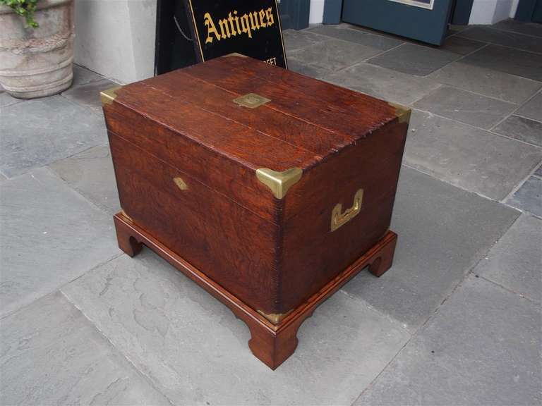 English Oak campaign chest on stand with hinged top, original brass mounts and side handles, baise lined interior, and resting on stand with bracket feet.  Stand was made at later date for chest.  Early 19th Century