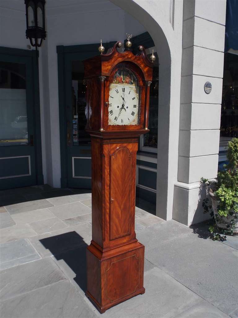 English Chippendale Mahogany tall case clock with broken pediment, brass finials with eagle, Corinthian columns, painted Royalty face, brass string inlay, and terminating on squared plinth.  Clock is in working condition. 18th Century.