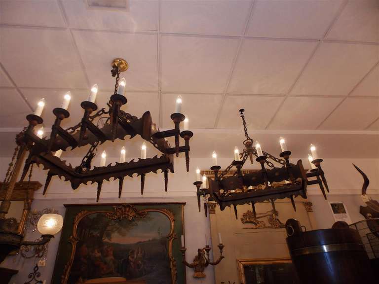 Pair of French wrought iron and gilt twelve light hanging chandeliers with centered gilt sphere.  Originally candle powered and have been electrified.  Early 19th Century