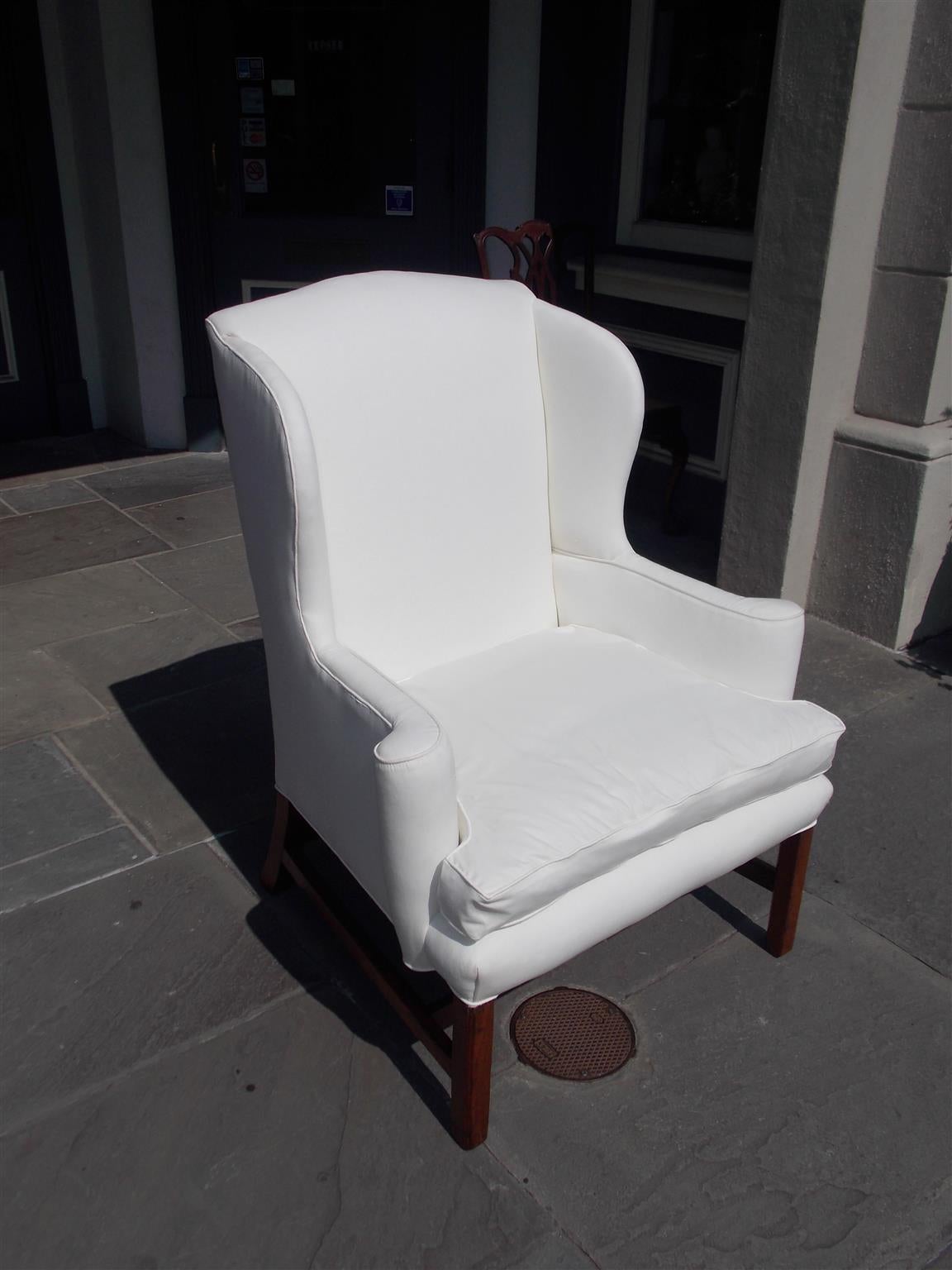 English Chippendale walnut wing back chair with a straight back, scrolled arms, and terminating on reeded blocked legs with cross stretchers, Late 18th century. Chair is upholstered in white muslin.