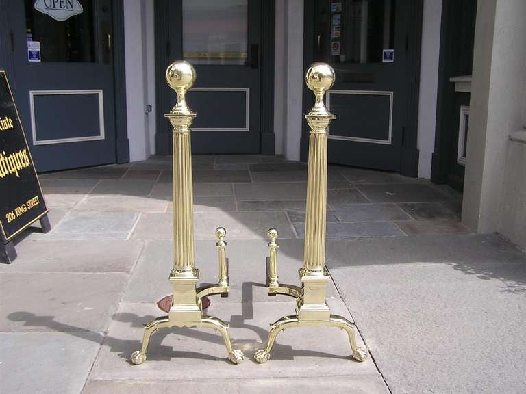 Pair of American brass ball top andirons  with fluted centered columns, squared scalloped plinths, and terminating on double spur leg, ball and claw feet with original matching log stops.  Dealers please call for trade price.  