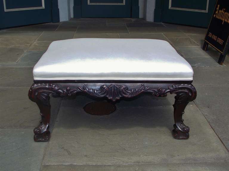 English Chippendale mahogany ottoman with carved acanthus and shell motif, upholstered seat, and terminating on carved scrolled foliage feet. Ottoman is covered in white muslin.  Late 18th Century