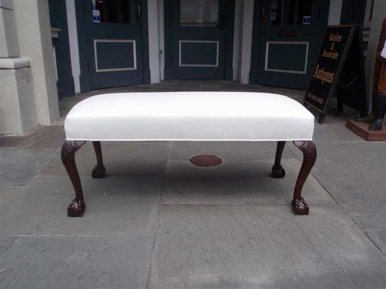 English mahogany upholstered bench with carved acanthus knee and terminating on tapered legs with ball and claw feet.  Bench is covered in white muslin.  Mid 19th century