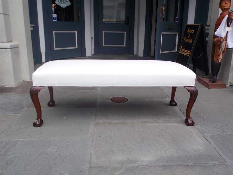 English mahogany upholstered bench with carved shell knee and terminating on tapered legs with ball and claw feet.  Bench is covered in white muslin.  Mid 19th century