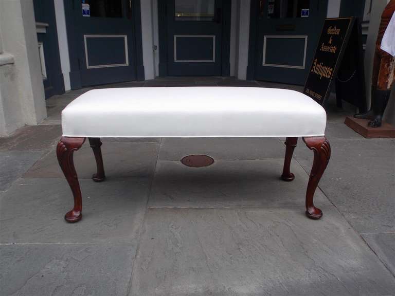 English mahogany upholstered bench with carved shell knee and terminating on tapered legs with pad feet.  Bench is covered in white muslin.  Mid 19th century
