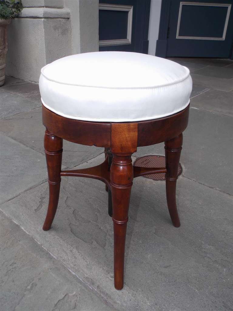 English mahogany swivel top upholstered piano stool with centered supporting stretchers, and terminating on bulbous tapered legs.  Stool is upholstered in white muslin. Early 19th Century.