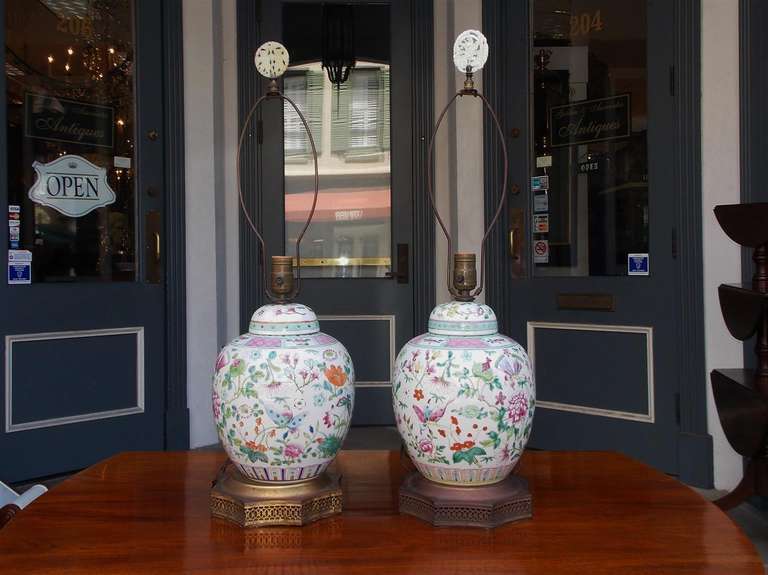 Pair of Japanese porcelain ginger jar table lamps with hand painted floral scenes, resting on gilt bronze filigree base. Mid 19th Century. Jars have been converted to lamps.