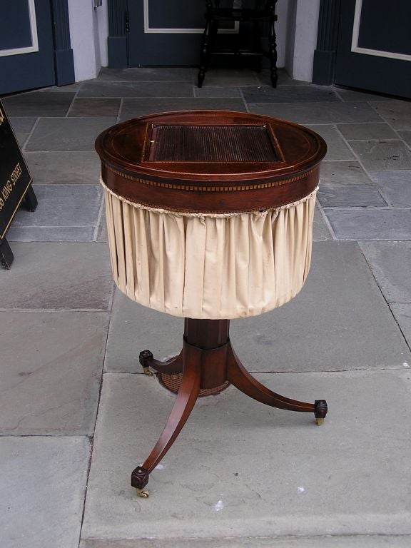 English mahogany tambour  circular sewing table with satinwood inlay,  fitted compartmentalized interior , silk upholstery , and terminating on splayed tripod cuffed legs with the original brass casters. Late 18th Century