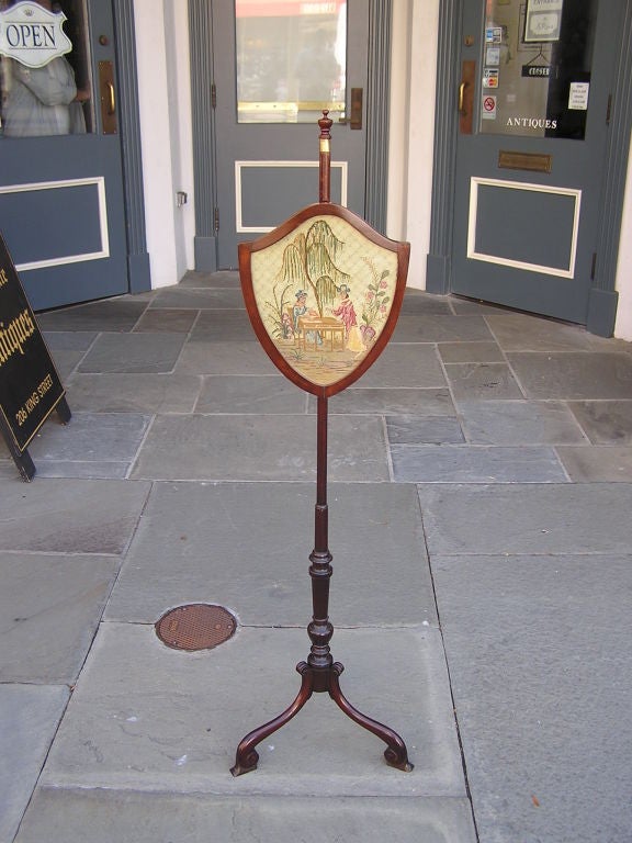 English Chippendale mahogany shield back needlepoint pole screen with a urn finial , telescopic turned bulbous shaft,  and terminating on tripod scrolled feet.  Late 18th Century