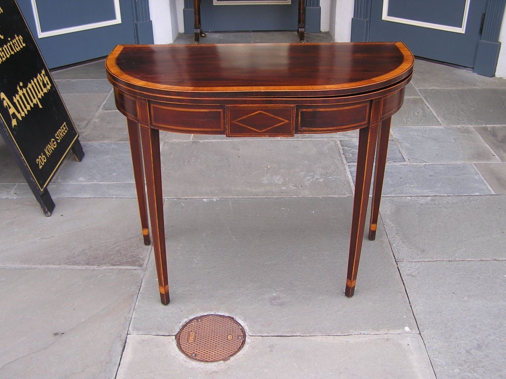 Charleston Hepplewhite mahogany demi-lune hinged games table with central diamond satinwood inlay , flanking rectangular satinwood inlaid panels, cross banded inlaid one board top , and terminating on squared tapered cuffed legs. Secondary woods