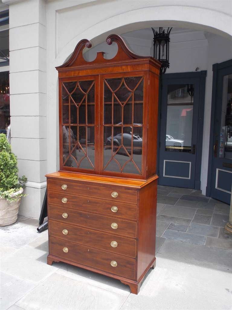 English mahogany fall front secretary with floral carved broken pediment, flanking upper glass doors with adjustable shelves, Satinwood string inlay, fall front desk with fitted interior and original pulls over three graduated lower drawers with