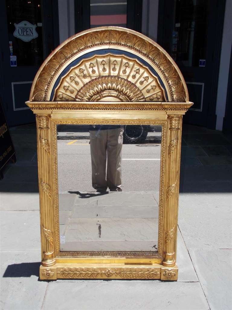 Miroir mural russe en bois sculpté et gesso, avec une corniche arquée en lapis peint, des colonnes d'acanthe cannelées, et un décor de langue d'agneau, de fleur de cloche, de perles intérieures et de filigrane de feuillage. Le miroir conserve le