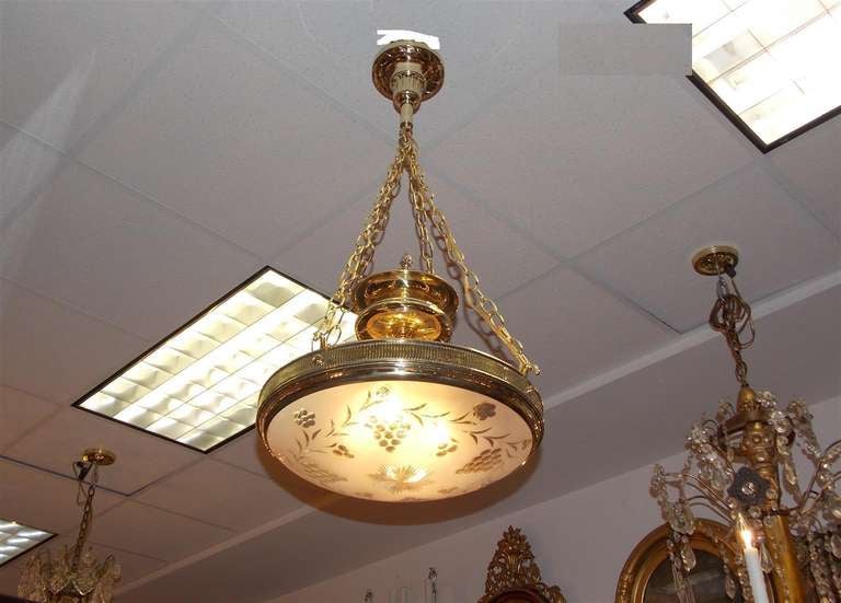 American brass four light chandelier with etched grapevine  frosted globe and centered brass urn oil reservoir.  Dealers please call for trade price.