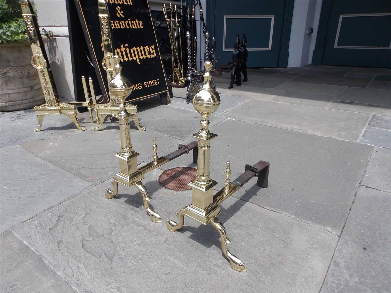 Pair of American brass ball top finial andirons with turned ringed centered columns, squared plinths, matching log stops and terminating on spur legs with slipper feet, Early 19th century, New York.