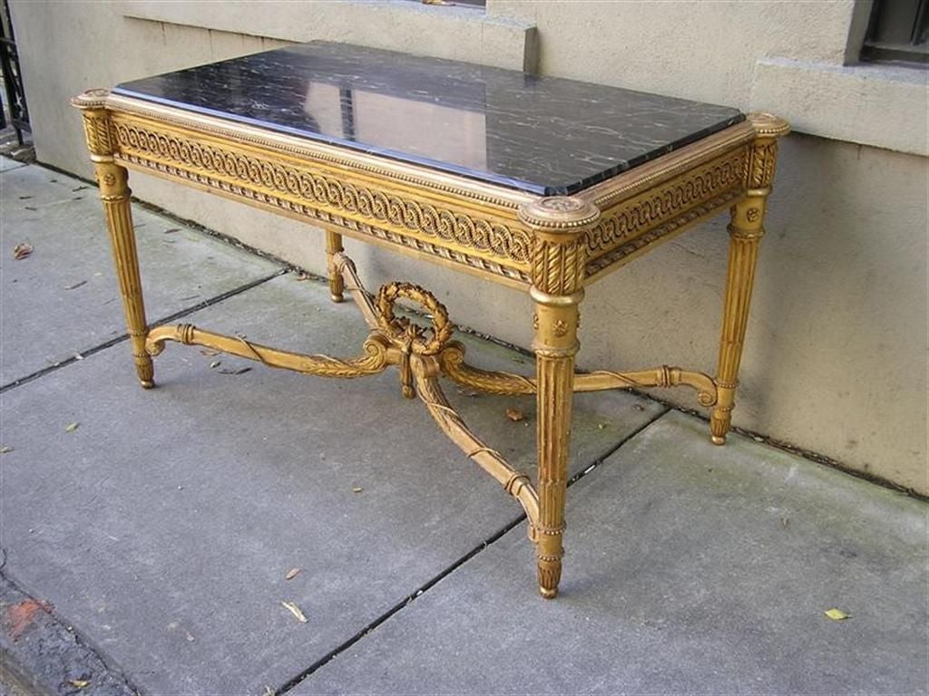 French gilt carved wood original marble top console with articulated carved skirt, fluted legs, and laurel wreath with twisted rope. Late 18th century