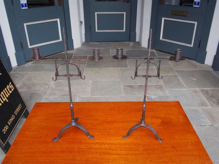 Pair of Italian wrought iron two candle candelabras with telescopic tapered spike and terminating on tripod stylized penny feet.  Dealers please call for trade price.