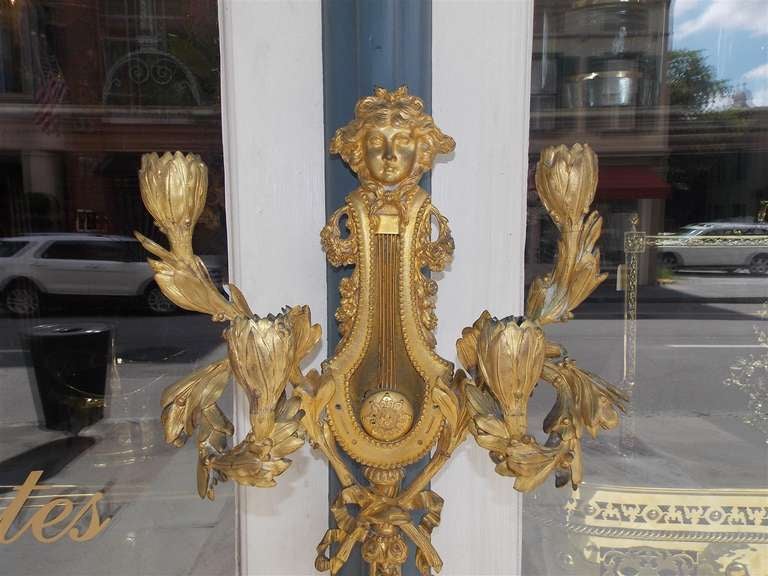 Pair of French Louis XVI gilt bronze foliage four arm sconces with centered figural lady over musical lyre, and finely decorated with tapered ribbon, and tassel motif. Pair are candle powered but can be electrified if desired. Late 18th Century