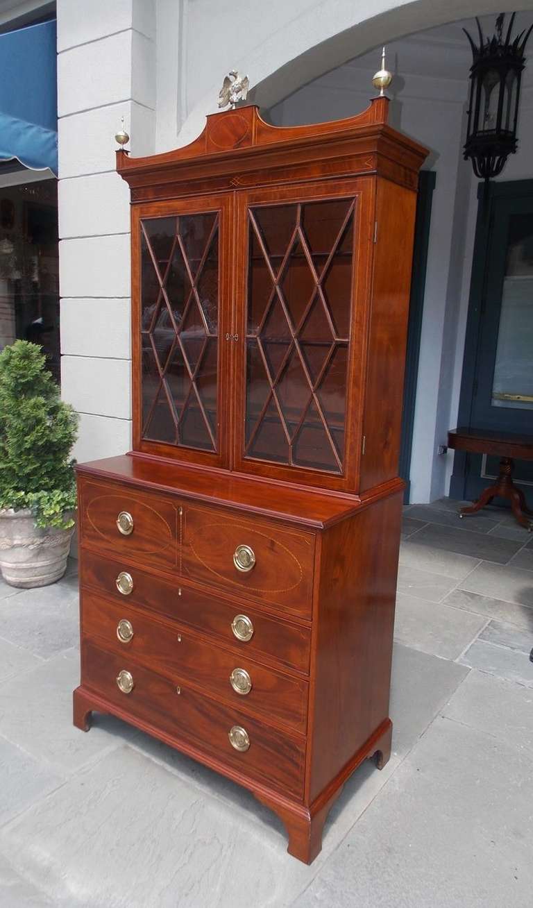 Charleston mahogany fall front secretary bookcase crowned with an inlaid oval string decorative cornice, brass eagle and urn finials, original glass doors with adjustable interior shelving, fitted lower interior leather writing surface, accompanied