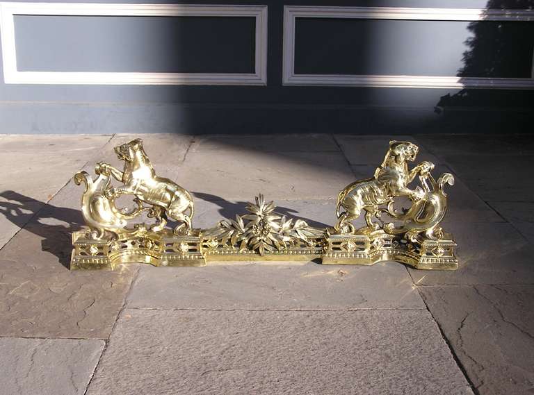 English brass three piece chenet with flanking tigers perched to strike against ornamental crest, hand chased beaded plinths,  with centered floral and berry motif.  Early 19th Century