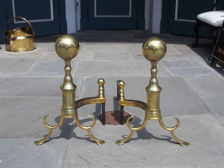 Pair of American brass andirons with ball tops, turned bulbous faceted plinths, matching ball finial log stops, double spur legs, and terminating on stylized penny feet.  Boston, Late 18th Century.