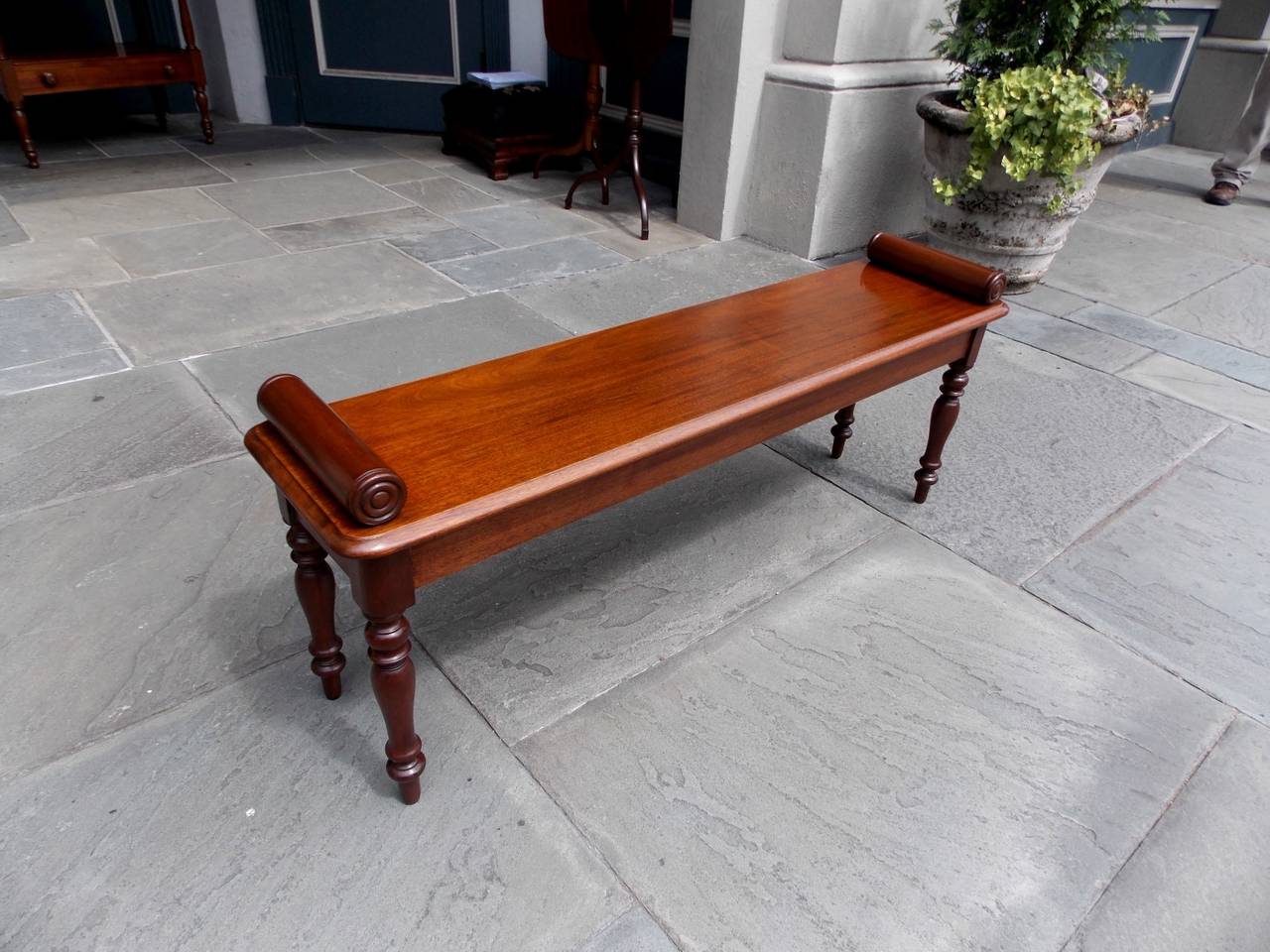 English Regency mahogany bench with flanking horizontal pillars, one board seat, and terminating on turned bulbous legs, Early 19th Century.