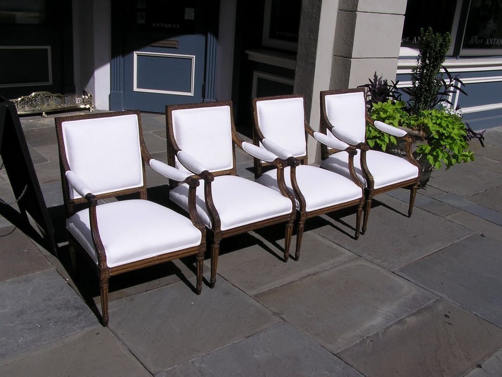 Set of four French carved wood gold gilt arm chairs with floral motif and fluted legs.