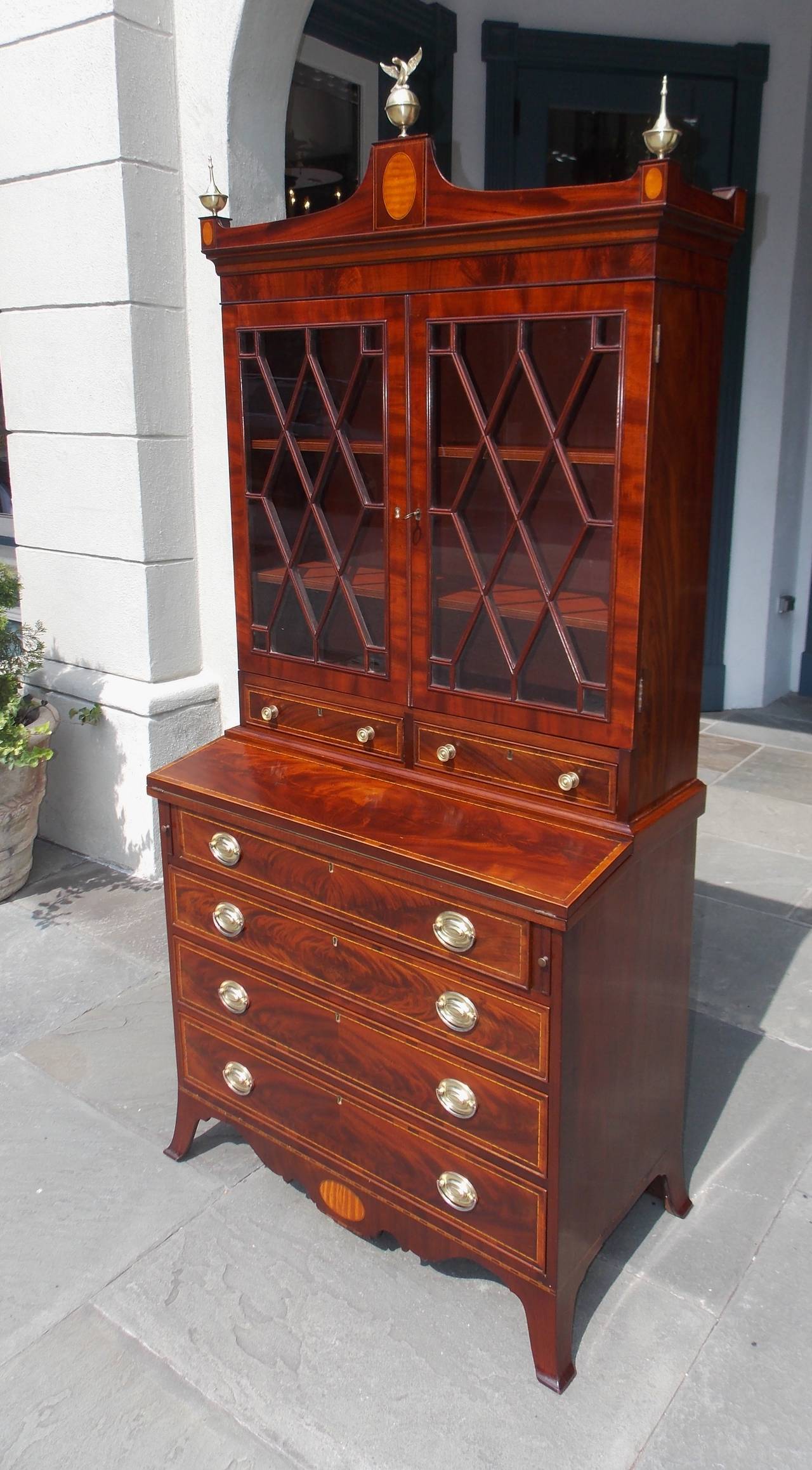 American Hepplewhite mahogany and satinwood fall front secretary bookcase with upper adjustable interior shelving, eagle and urn brass finials, original flanking glass paneled doors over two drawers, original brasses, satinwood oval inlays,
