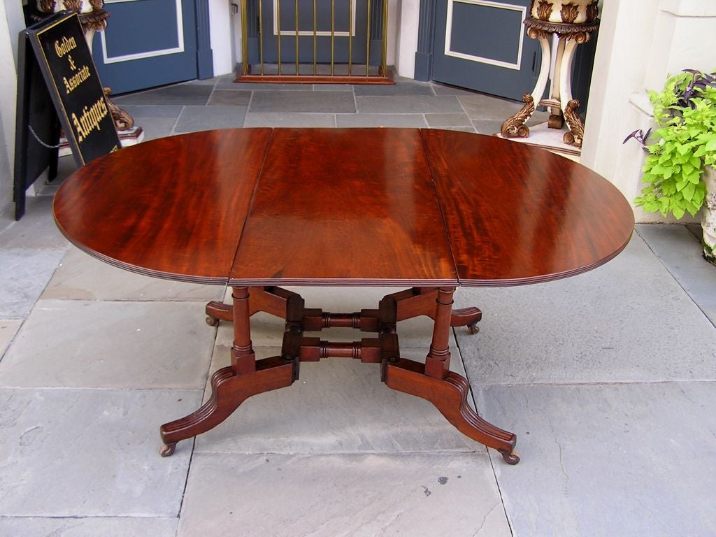 American Regency Cuban mahogany sutherland drop leaf table with turned reeded legs and original wood casters.