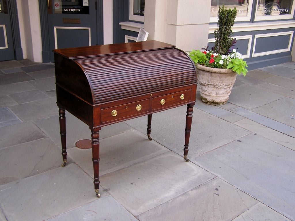 English mahogany Sheraton tambour desk with fitted interior Satinwood drawers, original brass pulls, and pigeon holes. Desk has a sliding tilt baize writing surface over two lower drawers with the original brass pulls.  Desk rest on the original