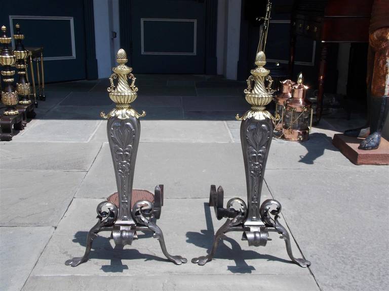 Pair of Italian wrought iron and brass andirons with acorn and urn top final, chased acanthus tapered plinths, matching log stops, spit hooks, and terminating on stylized clover feet.  Early 19th Century