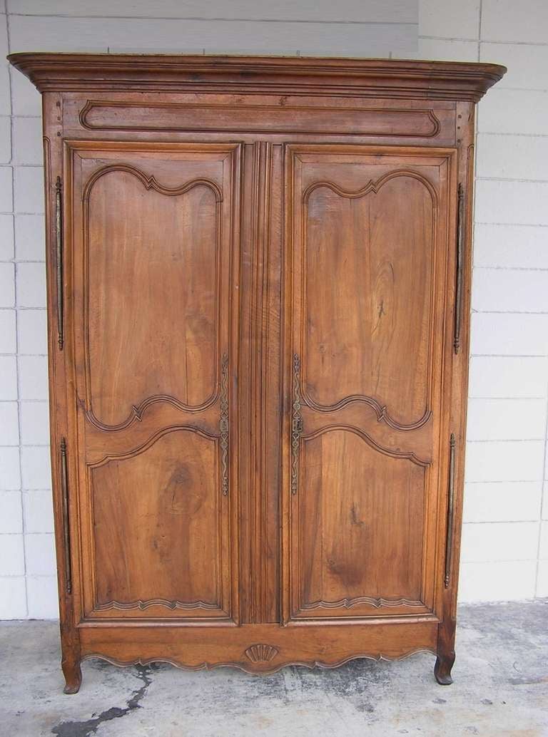 French Provincial Walnut two door hinged armoire with scrolled floral & shell carving , original polished steel hardware, brass escutcheons, and terminating on cabriole feet. Late 18th Century.  Armoire can be fitted with shelves or hanging bar. 