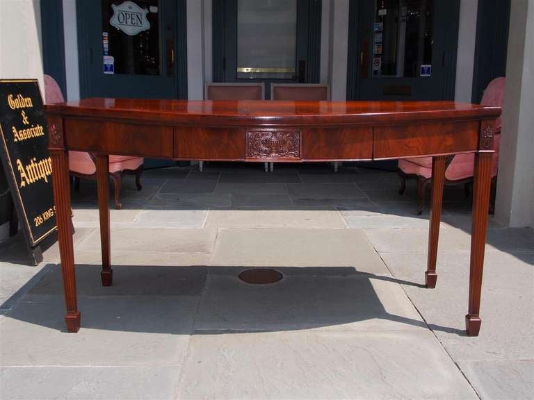 English mahogany one drawer bow front server with one board top, carved centered floral urn, oval floral medallions, and terminating on fluted legs with spade feet.  Dealers please call for trade price.