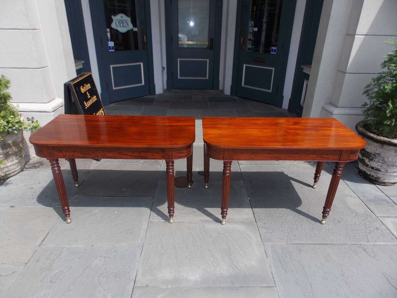 Pair of American Sheraton mahogany D-end console tables with one board tops, recessed ribbon mahogany skirts, reeded turned bulbous legs, and terminating on original brass ball feet . All Original .Secondary wood consists of white pine. N.Y.  Early