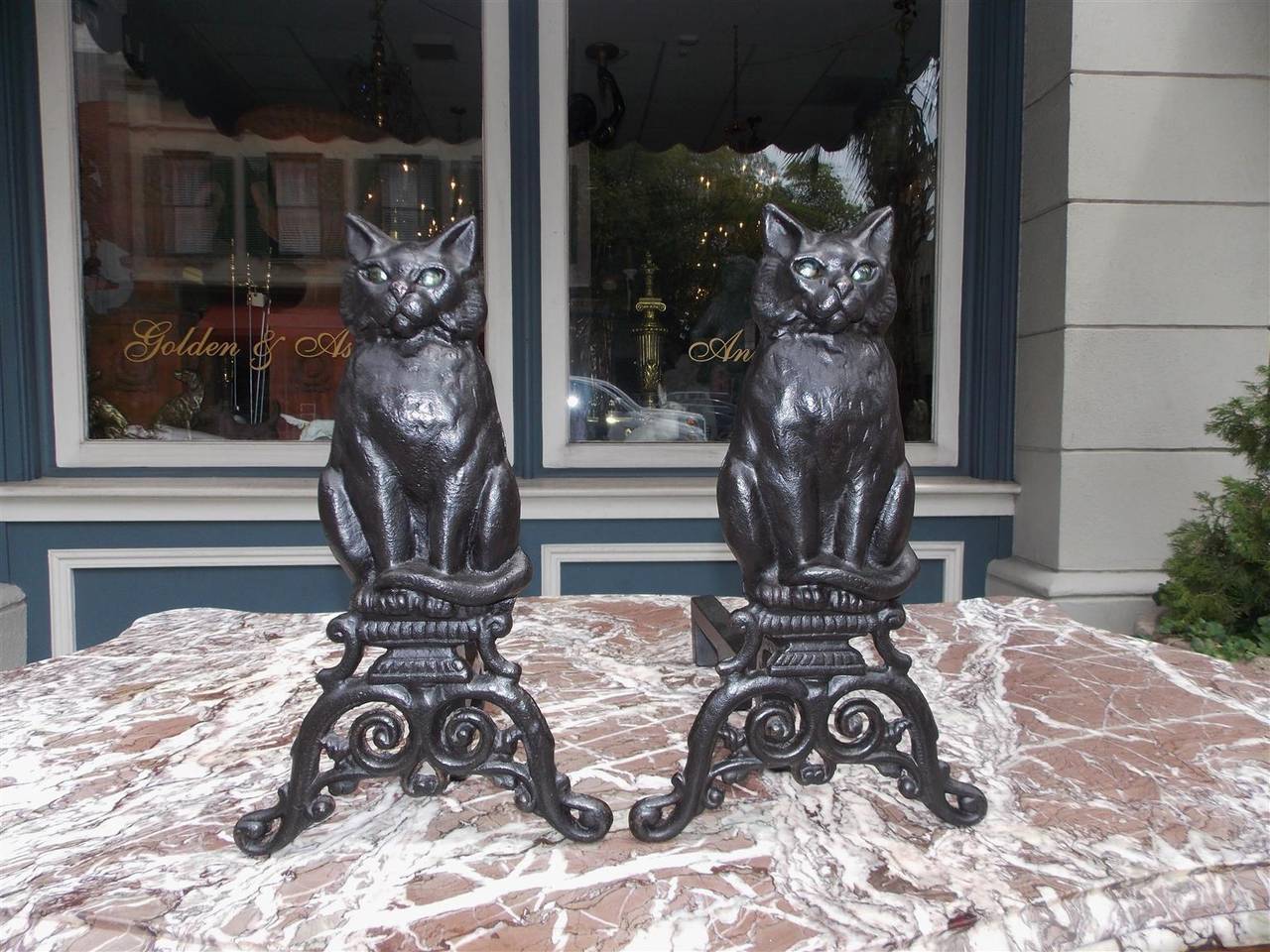 American cast iron perched cat andirons on scrolled decorative plinths with the original bluish green eyes & supporting three leg cast iron returns. Mid 19th Century .