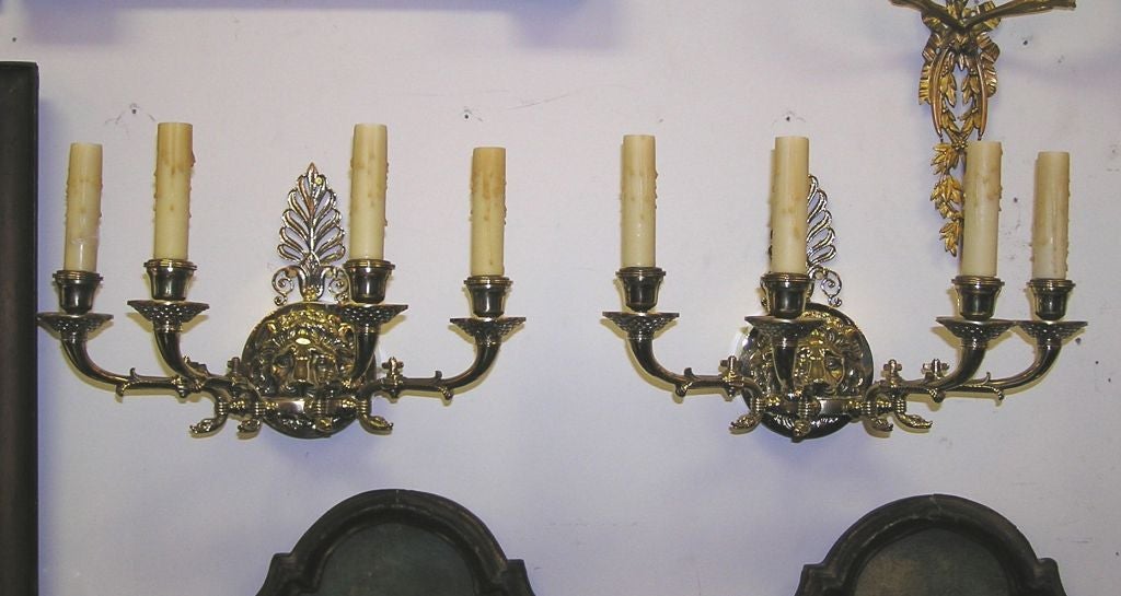 Pair of English brass central ring lion mask filigree four scrolled arm wall sconces with foliage brass bobeches, original cock keys, and decorative swans head motif. Originally gas and have been electrified. Early 19th Century