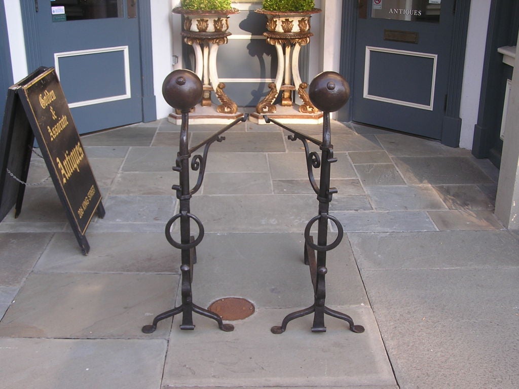 Pair of American wrought iron ball top andirons with rear swinging cranes, centered rings , spit hooks , and resting on scrolled legs with penny feet. 18th Century /  Acquired from Xalapa Farm in Paris, KY. Thoroughbred horse breeding farm founded