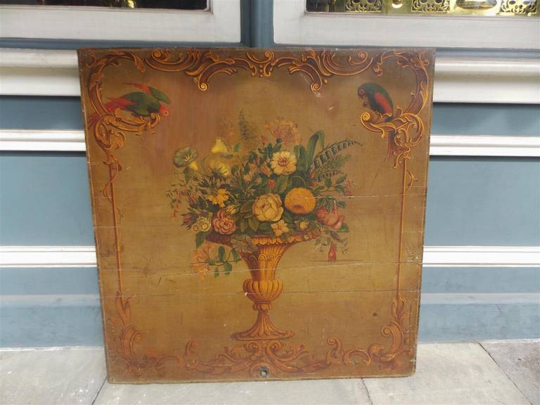 Italian hand painted oil on board still depicting centered floral urn with flanking parrots resting on decorative floral painted border.  Early 19th Century.