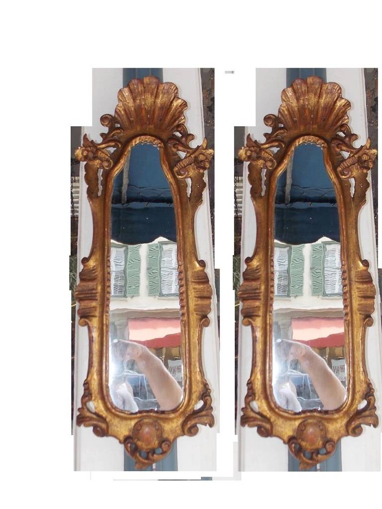 Pair of Italian gilt carved wood wall mirrors with centered shell crest and carved scrolled floral medallion motif.  Mirrors retain the original glass and backing. Signed Italy.  Late 18th Century.