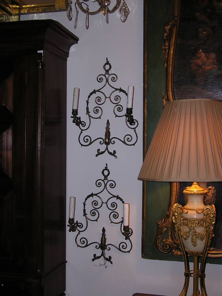 Zwei zweiarmige französische Bronzewandleuchter mit Lorbeerkranz und verschnörkeltem, floralem Motiv. Die Wandleuchter waren ursprünglich Kerzen und wurden elektrifiziert. Mitte des 19. Jahrhunderts.