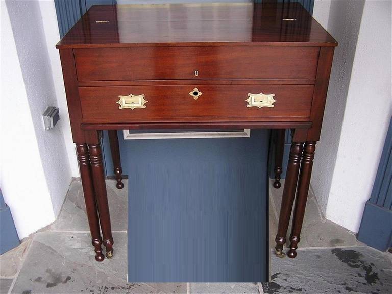 American Sheraton mahogany campaign desk with hinged flip top, pull out writing surface, recessed brasses, and terminating on turned bulbous legs. Early 19th Century